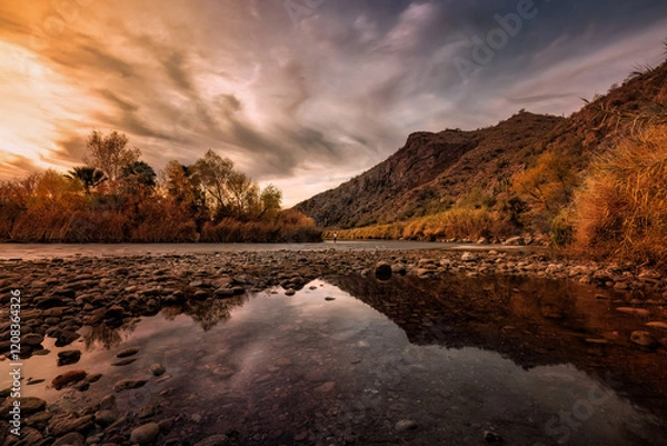 Fototapeta A beautiful sunset along the Salt River, with a fisherman doing some fly fishing, and a great reflection of the mountains.