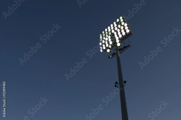 Obraz Lit stadium lights against evening sky
