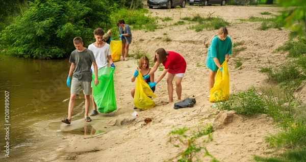 Fototapeta a group of student volunteers clean up trash on the beach