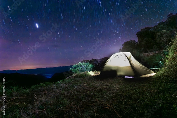 Fototapeta A camping tent on a mountain in a national park under a sky full of rotating stars