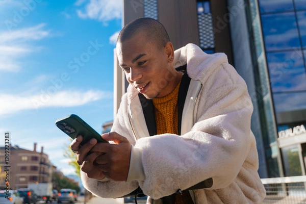Fototapeta Young man using mobile phone while riding electric scooter in the city