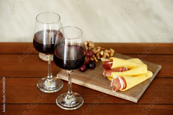 Fototapeta Glasses with red wine and tasty snacks on wooden table