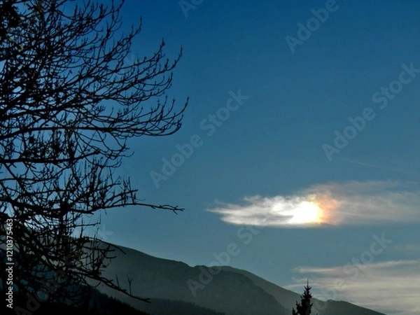 Obraz Colorful picturesque sky with Parhelion on Cirrostratus clouds over misty Tatras, Tatra Mountains in Poland and dark branches trees in autumn. Topics: optical phenomenon, air space, weather