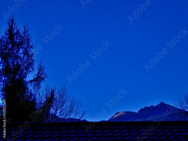 Fototapeta Abstract dark blue view with sky and dark horizon of mountain ranges with Kasprowy Wierch, Kasper Peak in Polish Western Tatras, Tatra Mountains over roof with roof tiles. Topics: Tatra National Park