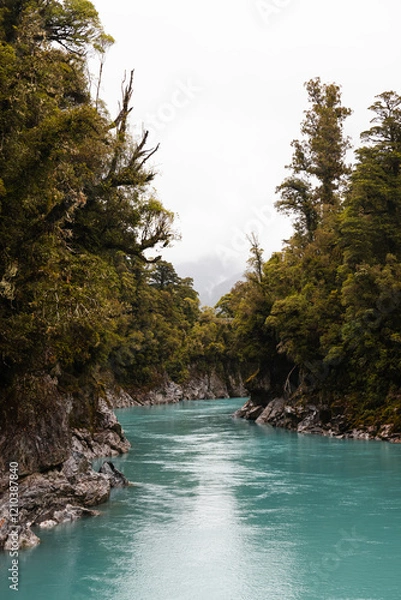 Obraz Turquoise calm water in Hokitika Gorge with fogs rolling through lush green forests on a rainy summer day (South Island, New Zealand)