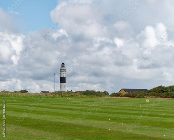 Fototapeta White lighthouse with a black stripe behind a meadow, Sylt, Germany