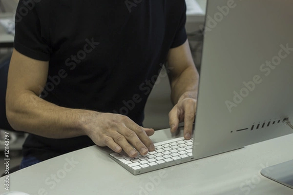Obraz Young man in a black T-shirt working with computer, man's hands on keyboard computer