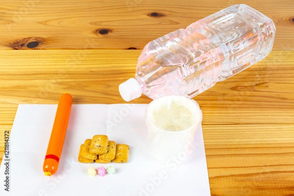 Obraz ビニール袋でカバーされた水が入った紙コップと避難所での一食の配給食料