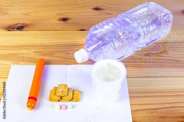 Obraz ビニール袋でカバーされた水が入った紙コップと避難所での一食の配給食料