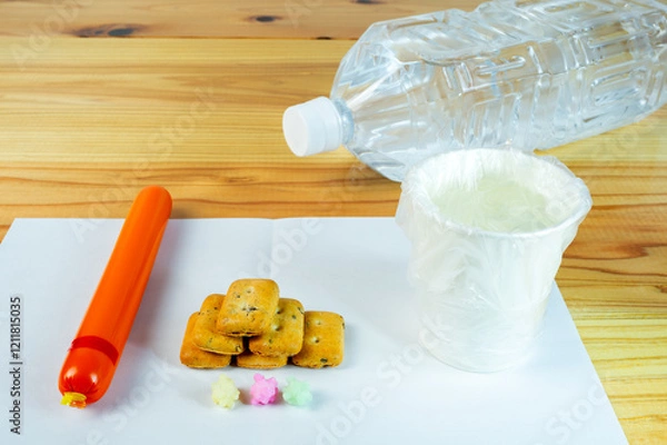 Obraz ビニール袋でカバーされた水が入った紙コップと避難所での一食の配給食料