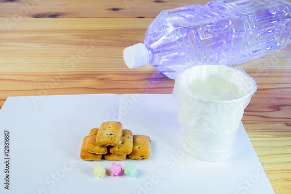 Fototapeta ビニール袋でカバーされた水が入った紙コップと避難所配給品の一食分の乾パン