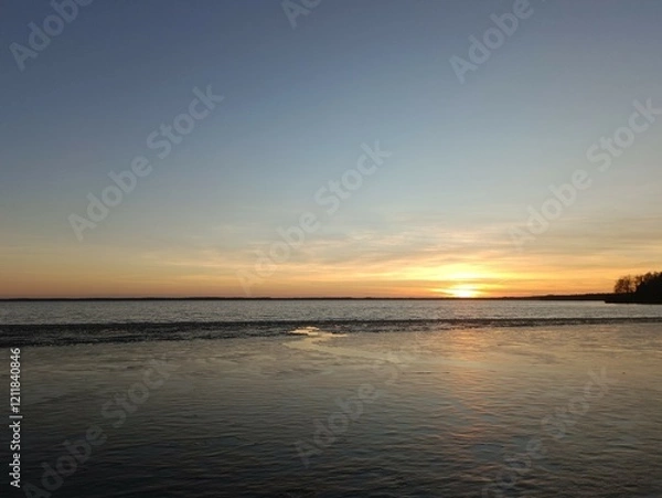 Fototapeta Red and yellow colored sunset over Rekyva lake. Sun set over lake. Some clouds are hangin in the sky. Blue yellow and red colored sky. Horizon over water. Saulelydis. Rekyvos ezeras.