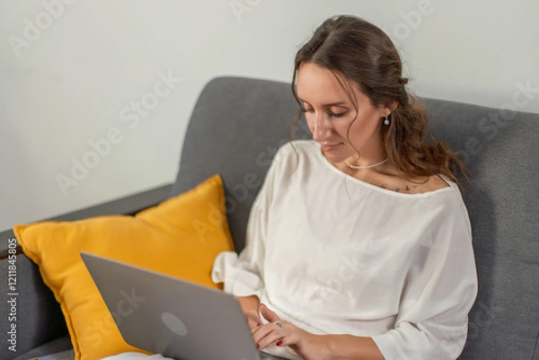 Fototapeta Woman Laptop Home Office: Working remotely from comfy couch, focused on laptop screen.