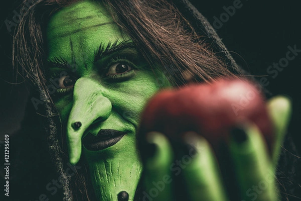 Obraz Evil witch looking at camera holding a red apple