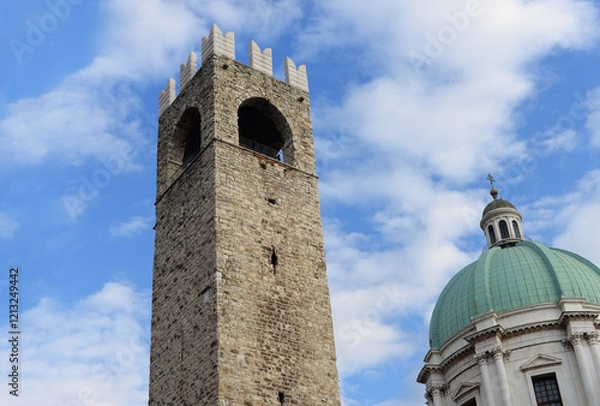 Fototapeta The Torre del Popolo on Palazzo Brolette and the dome of the Duomo Nuovo (New Cathedral) with blue sky and white fluffy clouds in Brescia, Italy