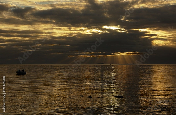 Obraz Sunrays over bay with small boat