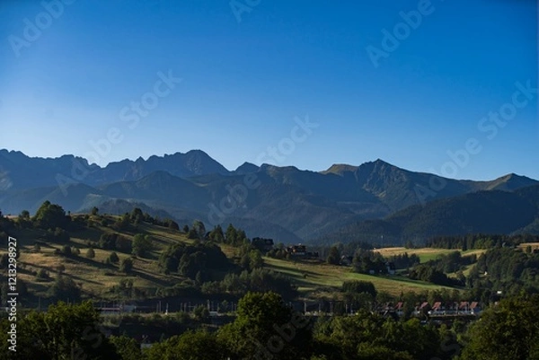Fototapeta Breathtaking view of mountain range under clear blue sky during early morning light in a serene landscape setting
