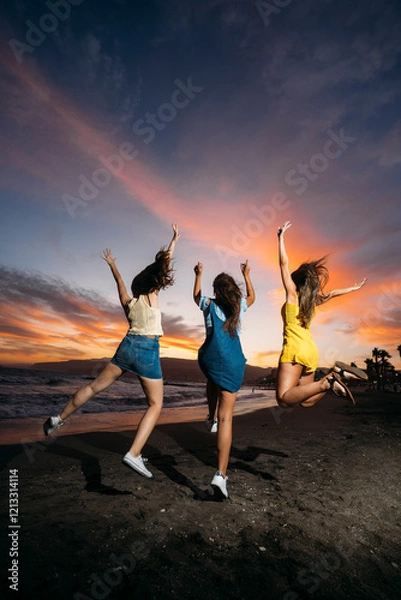 Obraz Three friends jumping on the beach at sunset