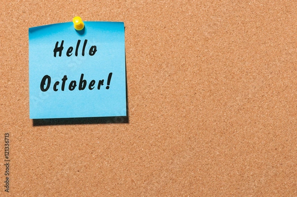 Fototapeta Hello October message on the blue sticker pinned at notice cork board. Autumn concept. With empty space for text