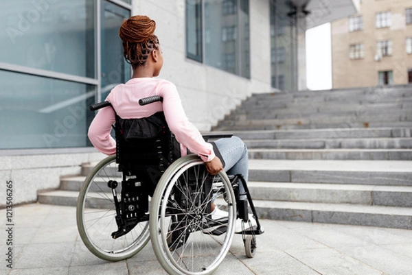 Fototapeta Disability, environment, mobility and social participation concept. Young black impaired lady in wheelchair cannot go up stairs without ramp, feeling limited and unhappy, copy space