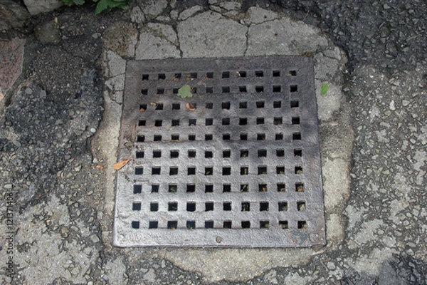 Obraz old rusty square cast iron manhole cover of storm sewer on aspha