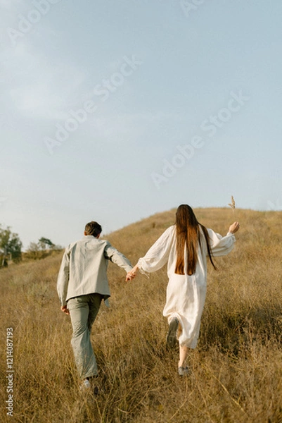 Obraz Young couple running through the hills. Love concept. Free spirit in nature. Beautiful field on the hills. Freedom concept. Uniting with nature.  Active lifestyle