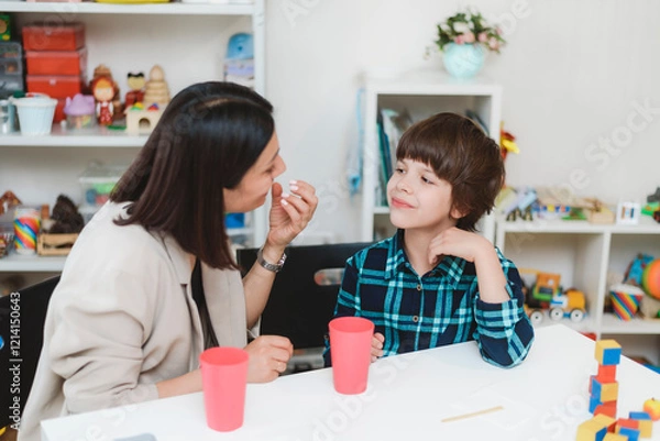 Obraz A cute boy with a speech therapist is taught to pronounce the letters, words and sounds.