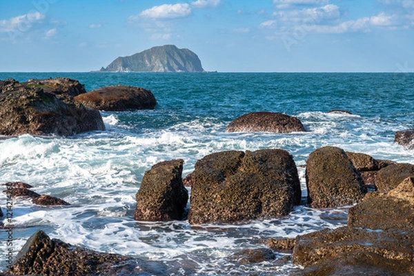 Obraz Gorgeous wave splashing on the rocks near the coastline, and Keelung island in the distance, in Keelung city, Taiwan.