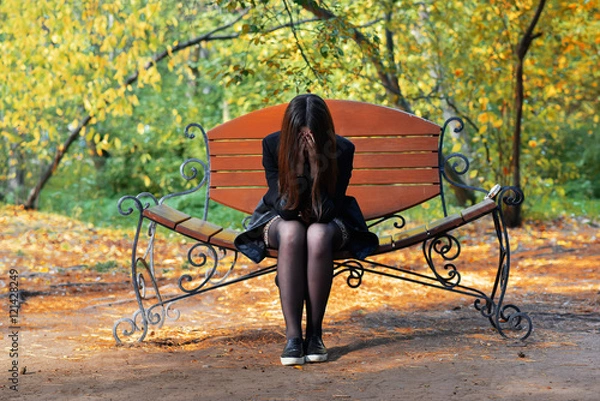 Obraz Girl sitting on the bench, covering face with his hands