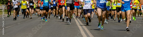 Obraz large group runners races down wide city street during marathon