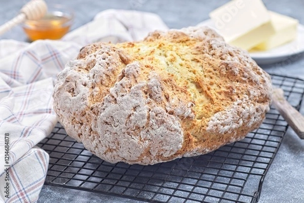 Obraz Freshly baked soda bread on cooling rack with butter and honey in the background, horizontal