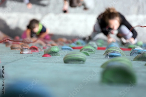 Fototapeta Artificial Climbing wall holds and blurred climbers