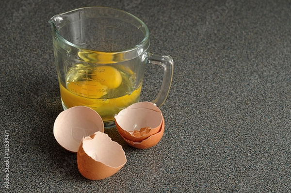 Obraz Two raw eggs in a measuring cup with egg shells