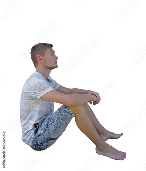 Fototapeta Pensive young man seated down looking up isolated over transparent background. Side view full length portrait thoughtful boy sitting