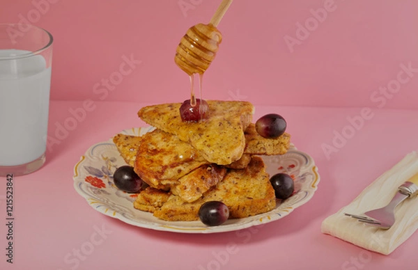 Fototapeta Slices of French toast with grapes and honey being drizzled over them.