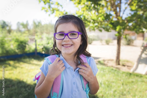 Obraz A girl wearing a uniform and a backpack is ready for her first day of school.