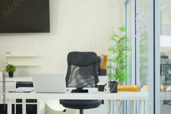 Fototapeta Modern office space with an organized desk, laptop, coffee cup, and stationery