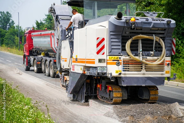Fototapeta An asphalt milling machine operating on a highway construction site, close up.