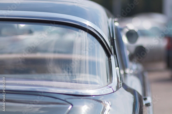 Fototapeta Close-up of an old car. Part of the exterior. An American classic. Chrome lining. Glass with reflection.