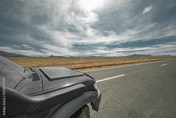 Fototapeta An off-road car with a solar panel stands on the highway with a view of the blue sky and the steppe. An electric car with a solar battery stands against the background of a steppe and a road.