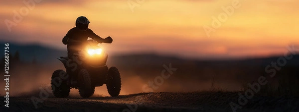 Fototapeta A rider navigates a quad bike on a dusty trail during sunset, capturing the thrill of off-road adventure in the fading light