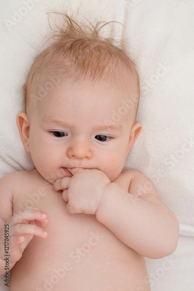 Fototapeta child beautiful happy boy with black eyes holds hands in mouth, close-up