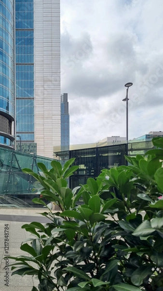 Fototapeta Sustainable glass office building with trees for reducing carbon dioxide. Eco-friendly building in modern city. Office with green environment. Corporate building reduce CO2.