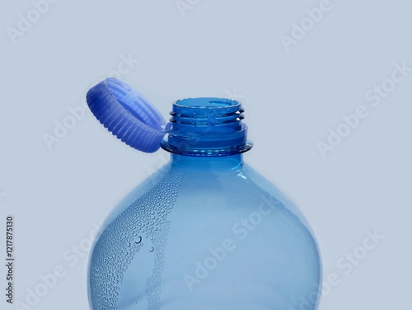 Fototapeta A new mechanism of plastic bottle with a stationary fixed tethered cap. Blue plastic PET water bottle with cup open close up isolated on white. Recycling, environment friendly and ecology concept