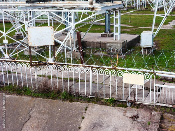 Obraz Restricted industrial equipment installation area fenced with barbed razor wire mesh atop of metal fence 