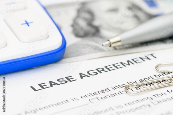 Fototapeta Lease agreement documentation and financial planning. A lease agreement, a calculator, pen, and paper clips, emphasizing financial calculations and legal preparations for rental or leasing contracts.