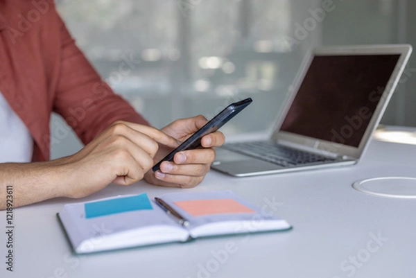 Fototapeta Man hands using phone inside office at workplace, man typing message on using online app to view investment reports.