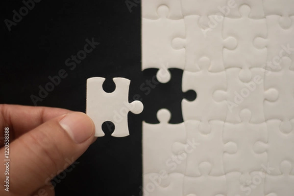 Obraz A man's hand is putting together a jigsaw puzzle.