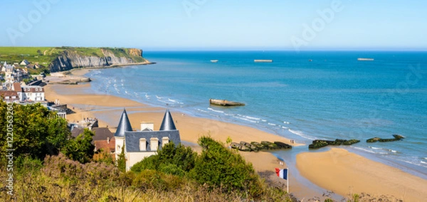 Fototapeta Panoramic view over Arromanches beach and Cap Manvieux in Normandy, France, on a sunny day, with remains of the WWII artificial Mulberry harbor lying on the sand and in the sea.