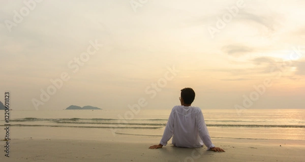 Fototapeta alone man sitting on the beach and looking sky at sunset, relax concept